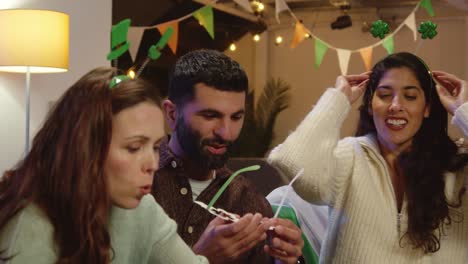 group of friends dressing up with irish novelties and props at home or in bar celebrating at st patrick's day party