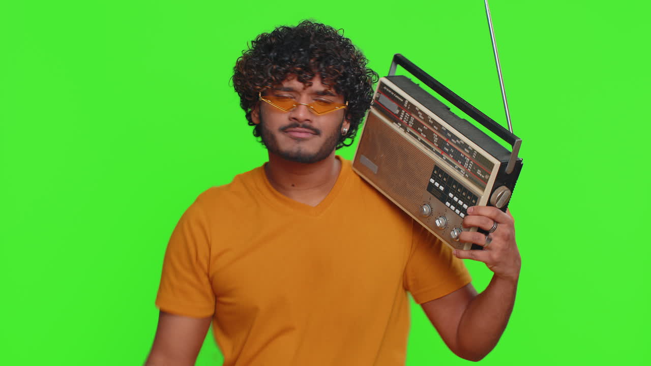 Uomo indiano che usa un giradischi retro per ascoltare musica disco ballando la sua canzone preferita divertendosi