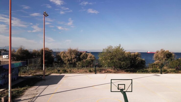 Clip da drone 4K sopra un campo da basket che sale verso il porto di Salonicco in Grecia.