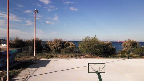 4K-Drohnenclip-über-Einem-Basketballplatz,-Der-Zum-Hafen-Von-Thessaloniki-In-Griechenland-Aufsteigt