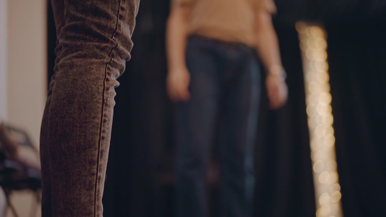 Closeup socked feet on stage floor, nervous performer grounding before audition with blurred instructor in background, soft string lights and dim studio mood, focus on balance posture and subtle