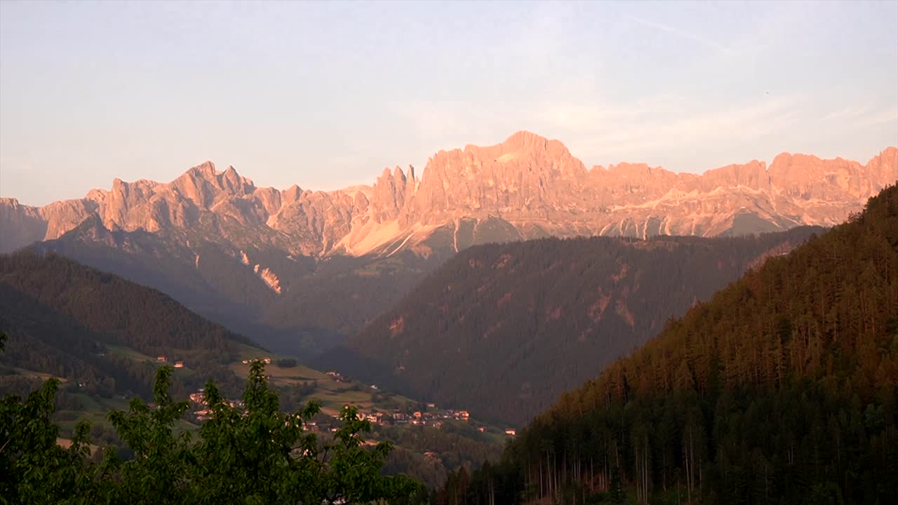 Pale di San Martino lyser lyserødt ved solnedgang over dalen i Dolomitterne