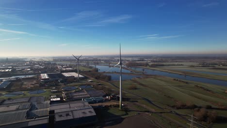 Wind-turbines,-water-treatment-and-bio-energy-facility-and-solar-panels-in-The-Netherlands-part-of-sustainable-industry-in-Dutch-flat-river-landscape-against-blue-sky