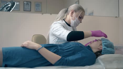 woman-in-mask-works-with-girl-eyebrows-form-in-salon