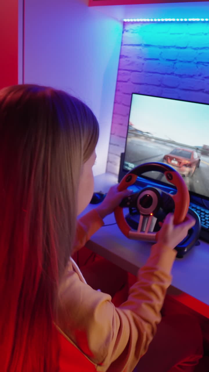 Teen playing racing computer game. Girl playing video game with racing wheels at home. Vertical video