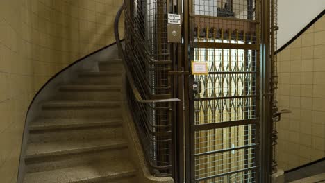 Wide-shot-of-an-old-vintage-elevator-going-up-and-arriving-empty-at-the-floor-of-a-building