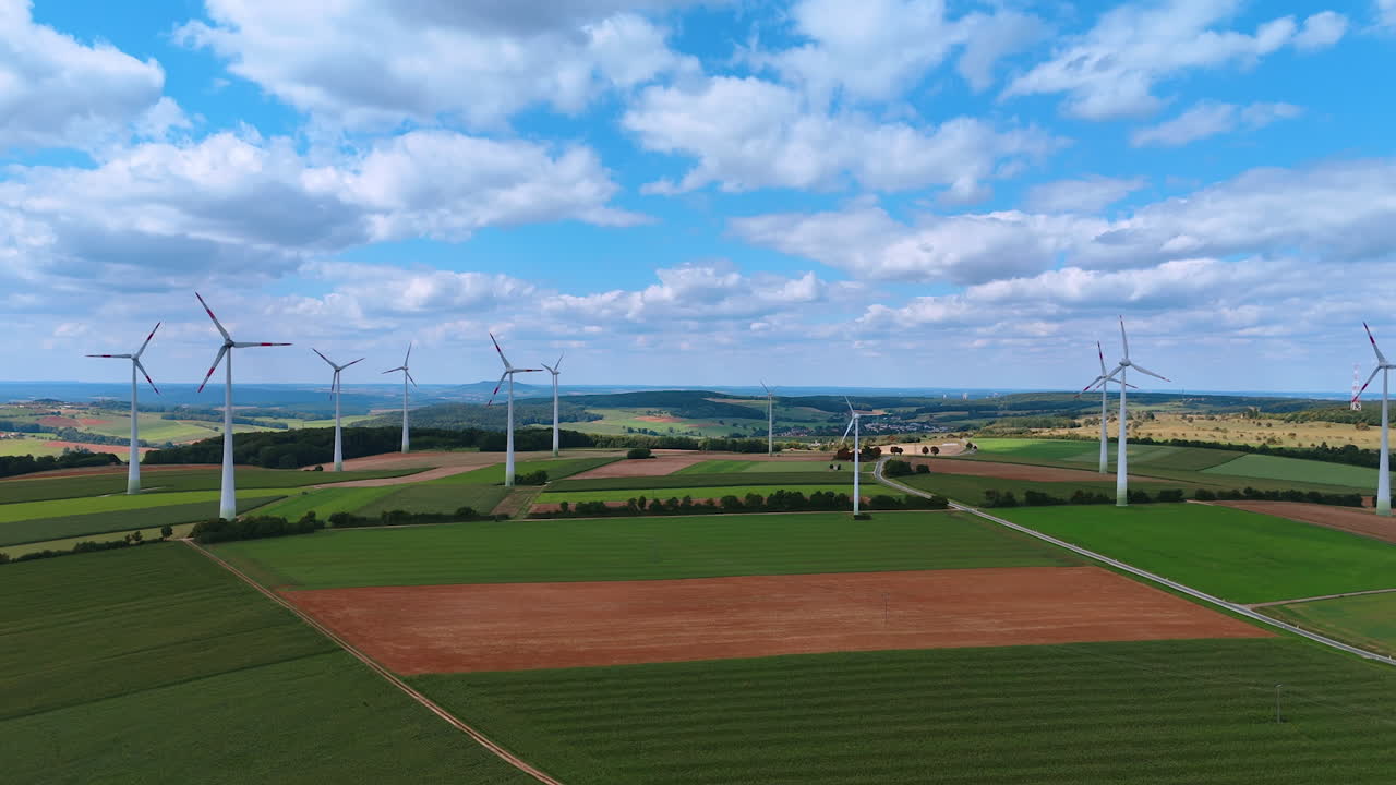 Beautiful countryside on cloudy summer day. Wind turbines rotate producing renewable energy. Drone footage