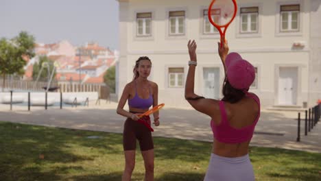Two women playing tennis in a park
