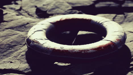 Lifebuoy resting on rugged rocks near shimmering water at sunset