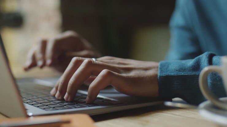 Mann tippt am Café-Tisch auf Laptop
