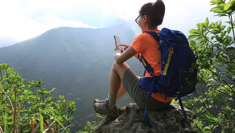 successful hiker using smartphone on sunrise mountain top cliff edge