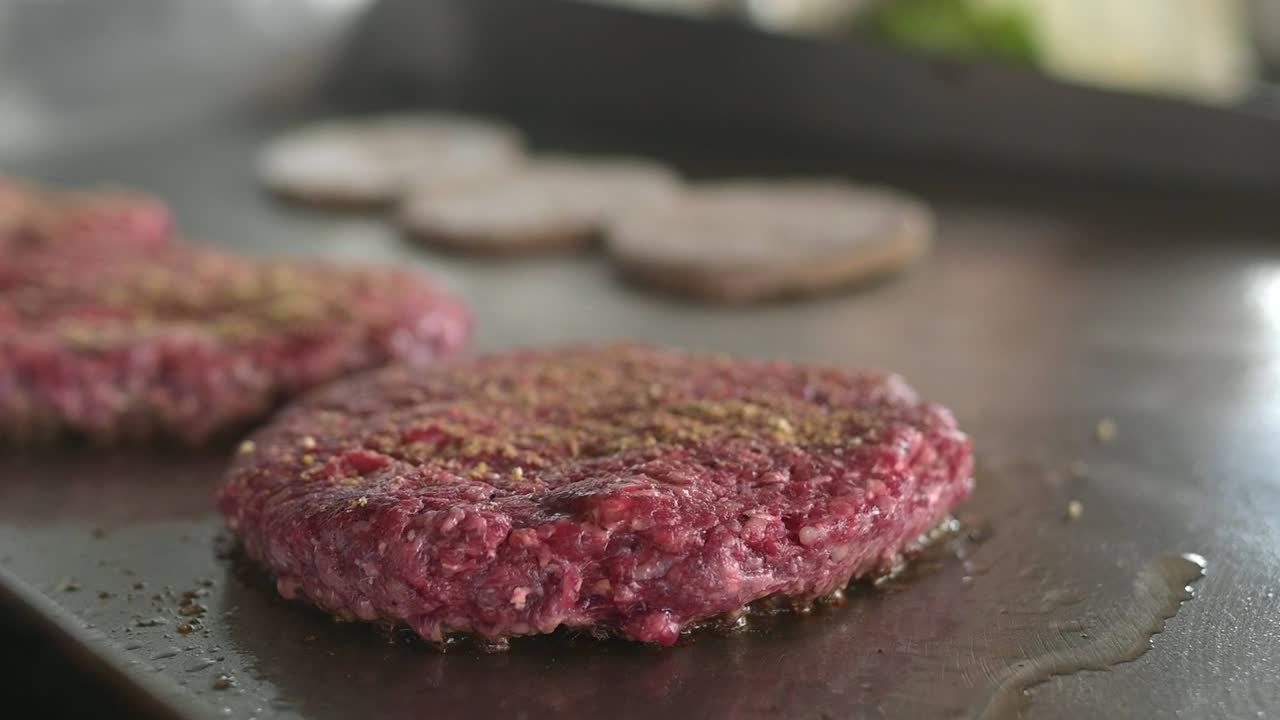 cocinero de cultivos asando bollos de hamburguesa y cocinando chuletas en la cocina