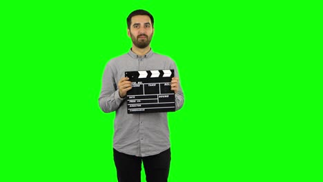 man holding a clapperboard on a green screen