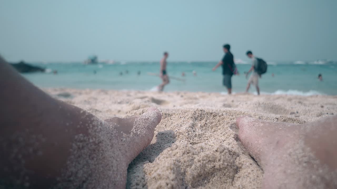 한 남자가 산책하는 관광객들과 함께 모래 해변에서 큰 발가락을 움직입니다.