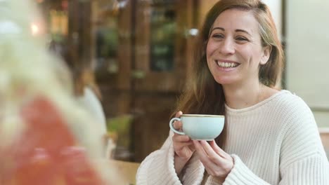 cheerful woman talking to unrecognizable partner in cafe