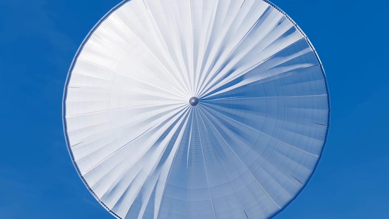 Tenda circolare bianca contro il cielo blu, che mostra pieghe radiali e trama tessile in uno stile pulito e minimalista.