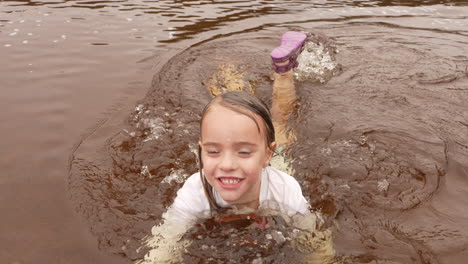 Niña-Alegre-Nadando-Y-Chapoteando-En-Un-Río-Fangoso,-Cámara-Lenta