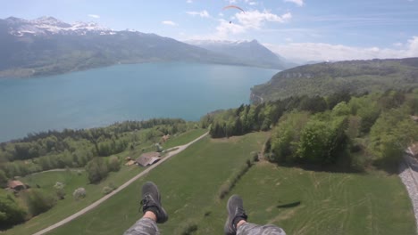 POV-Aufnahme-Eines-Gleitschirms,-Der-An-Einem-Sonnigen-Wintertag-über-Den-üppigen-Berg-Am-Ruhigen-Blauen-Fluss-In-Der-Schweiz-Fliegt-–-Luftaufnahme