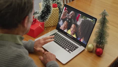 Caucasian-senior-man-on-video-call-on-laptop-with-family-at-christmas-time