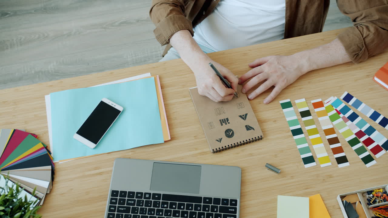 Designer working on logo design at a wooden desk