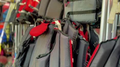 red and black life jackets hung in a row on hangers