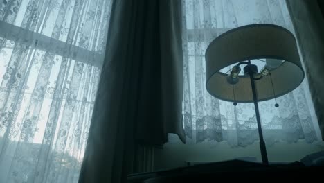 steady low angle view of beautiful round floor lamp with close curtains on windows in background, cozy interior ambiance.