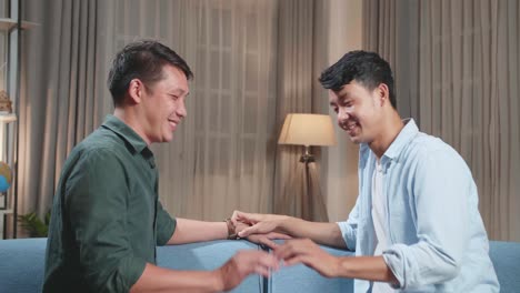 young asian adult gay couple spend time at home. two happy men in love in casual clothes gently hold hands. cute lgbt relationship content