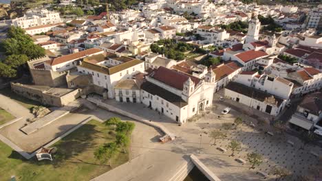 Antena-De-La-Antigua-Iglesia-Y-Castillo-En-Lagos,-Portugal,-Mientras-Surge-Un-Pájaro-Blanco-Que-Vuela