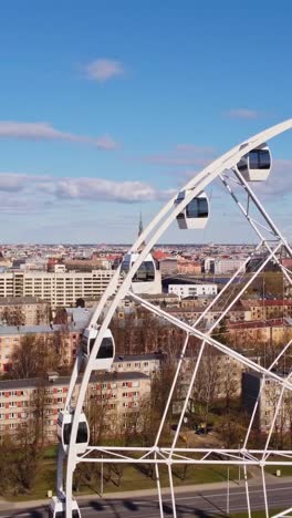 vertical ferris wheel spinning above cityscape on a sunny day in riga, latvia