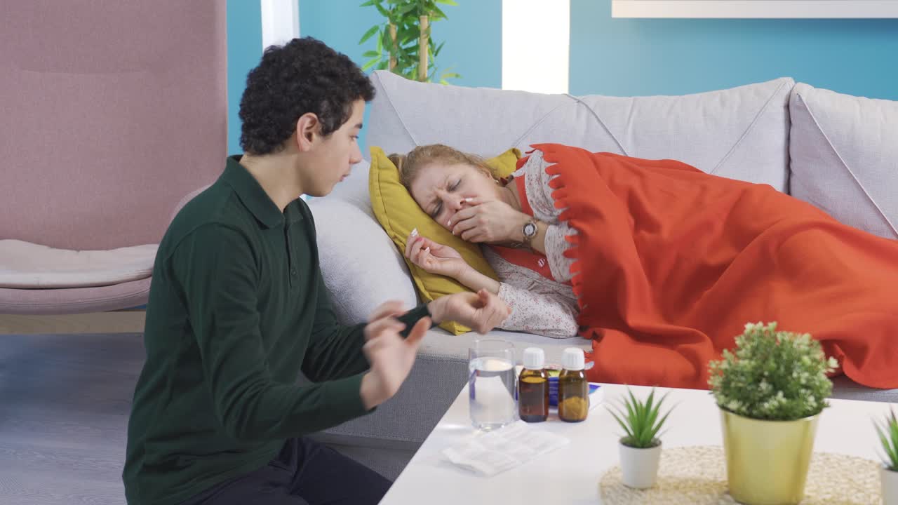 молодой человек приносит воду своей больной матери, чтобы она выпила ее лекарство.