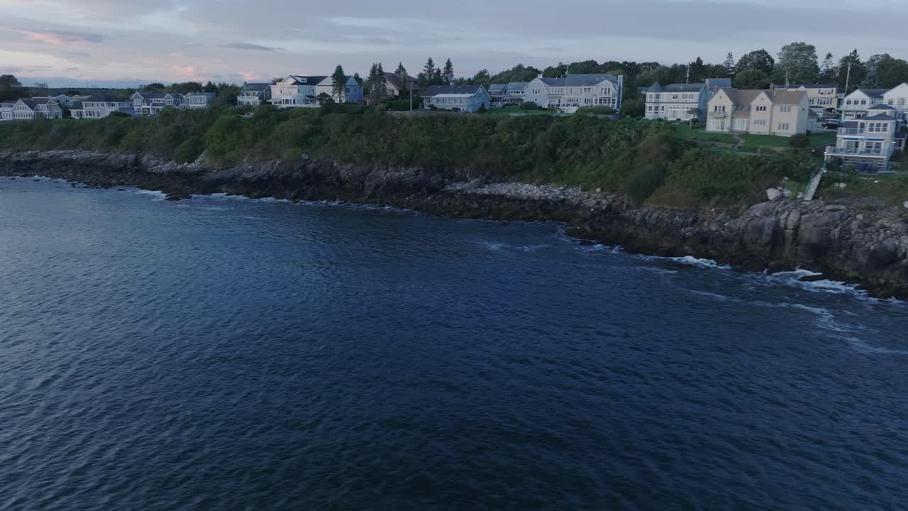 tomada aérea de drones de la playa de york, maine, panorámica a lo largo del cabo neddick, casas de la playa hacia la puesta de sol.