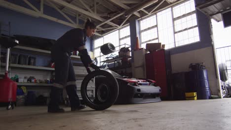 female mechanic rolling a tire to change at a car service station