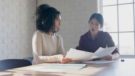 busy diverse casual businesswomen at table discussing project in office in slow motion