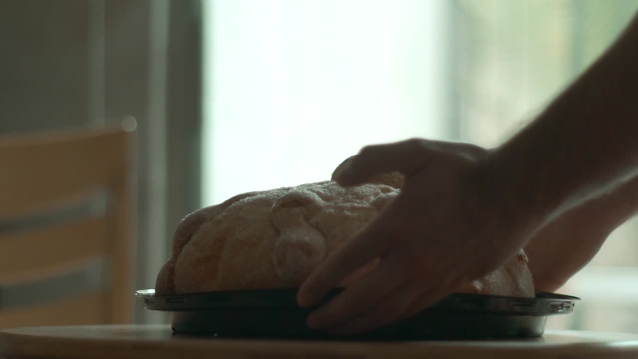 Person letting down a piece of pan de muerto in a table in slow motion
