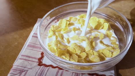 crispy yellow corn flakes into the bowl for the morning a delicious breakfast with milk. slow motion with rotation tracking shot.