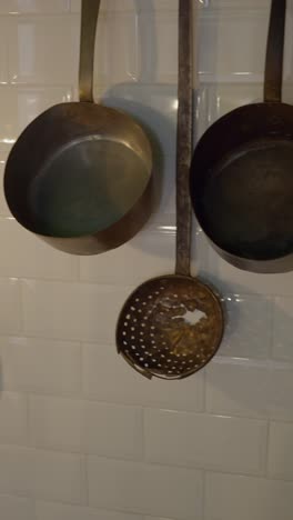 vintage brass kitchen ladles on white subway tiles