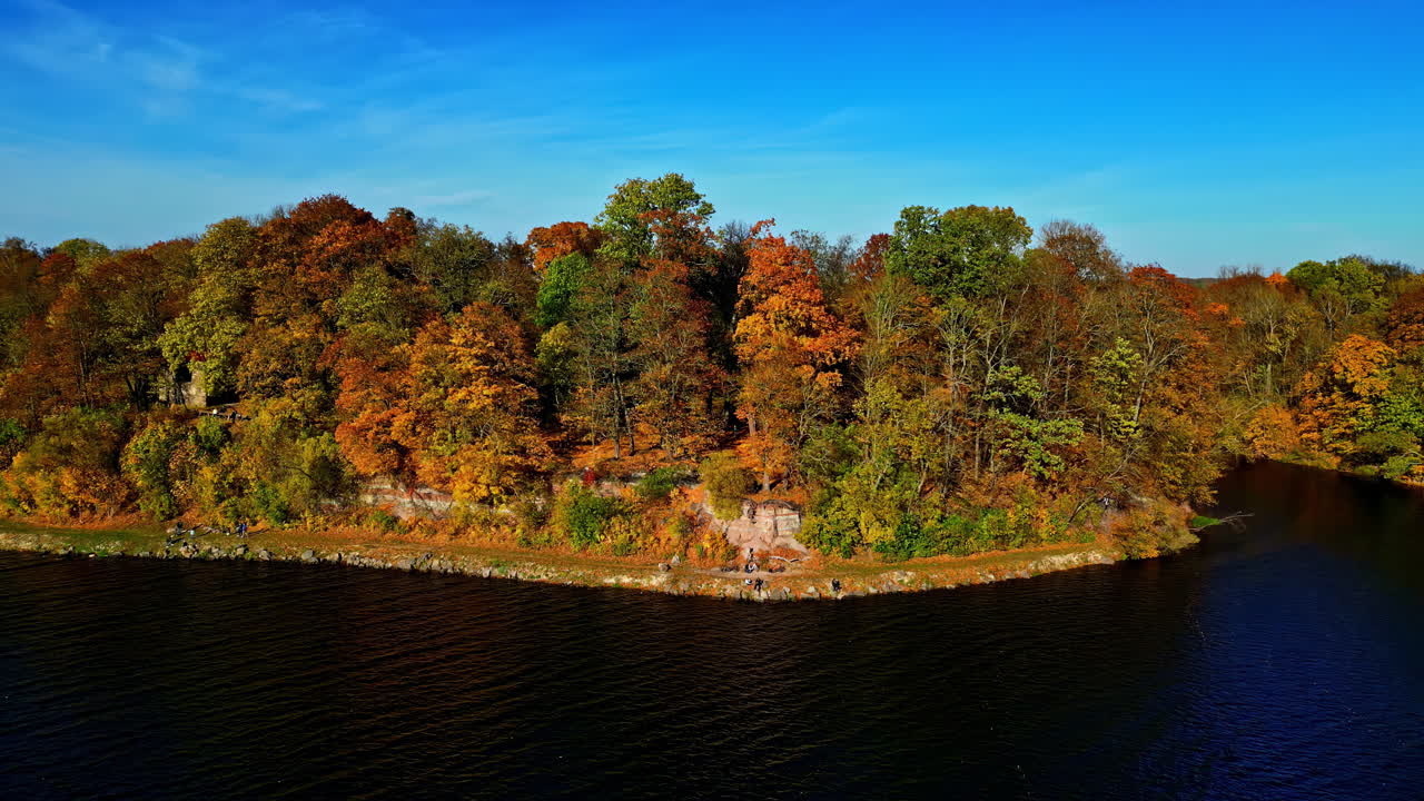 Drone capturing a forest during fall season with a riverfront