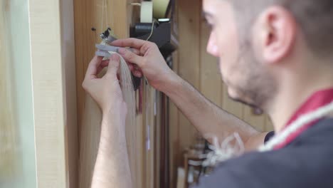 artesano profesional anónimo haciendo arco de violín y tomando medidas en el taller