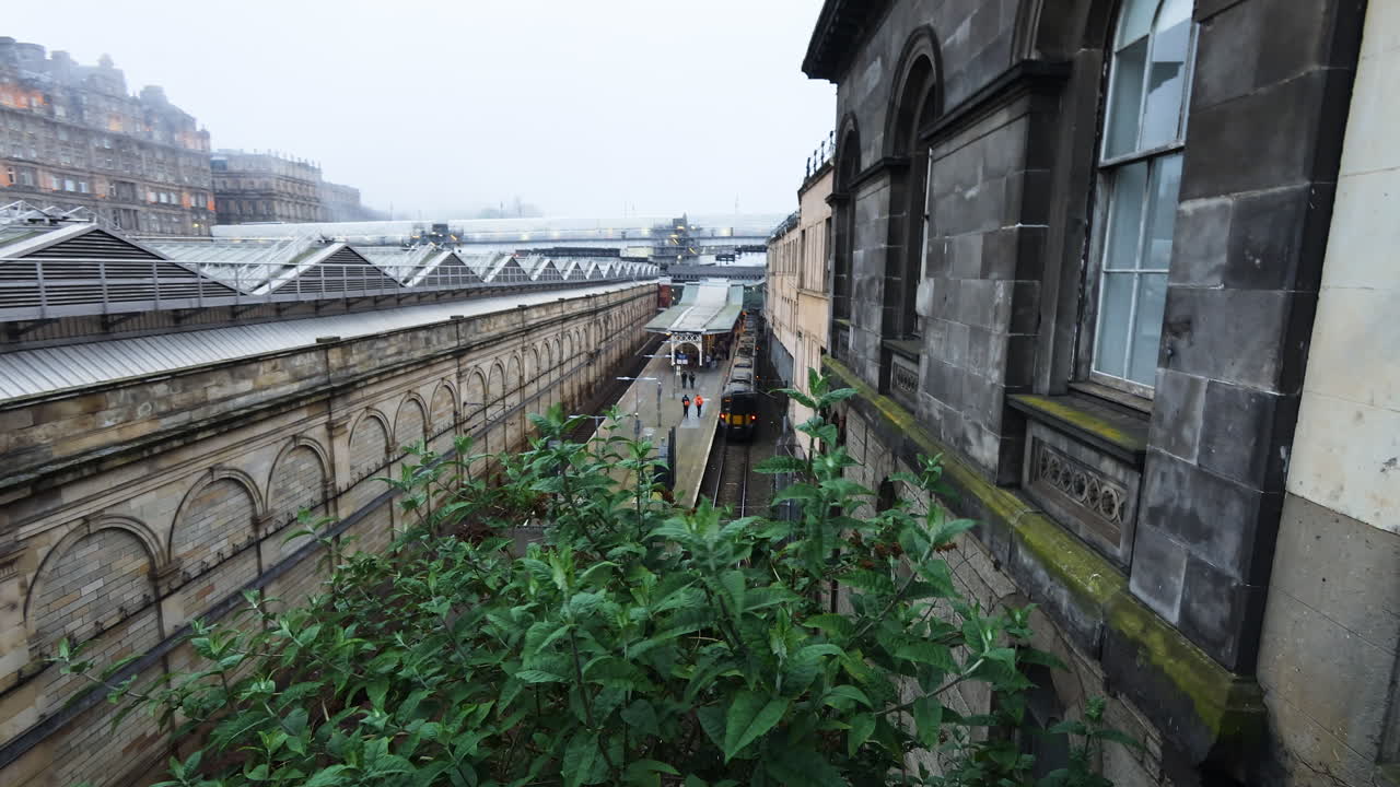 Treno in arrivo alla storica stazione di Edinburgh Waverley in una giornata nebbiosa.