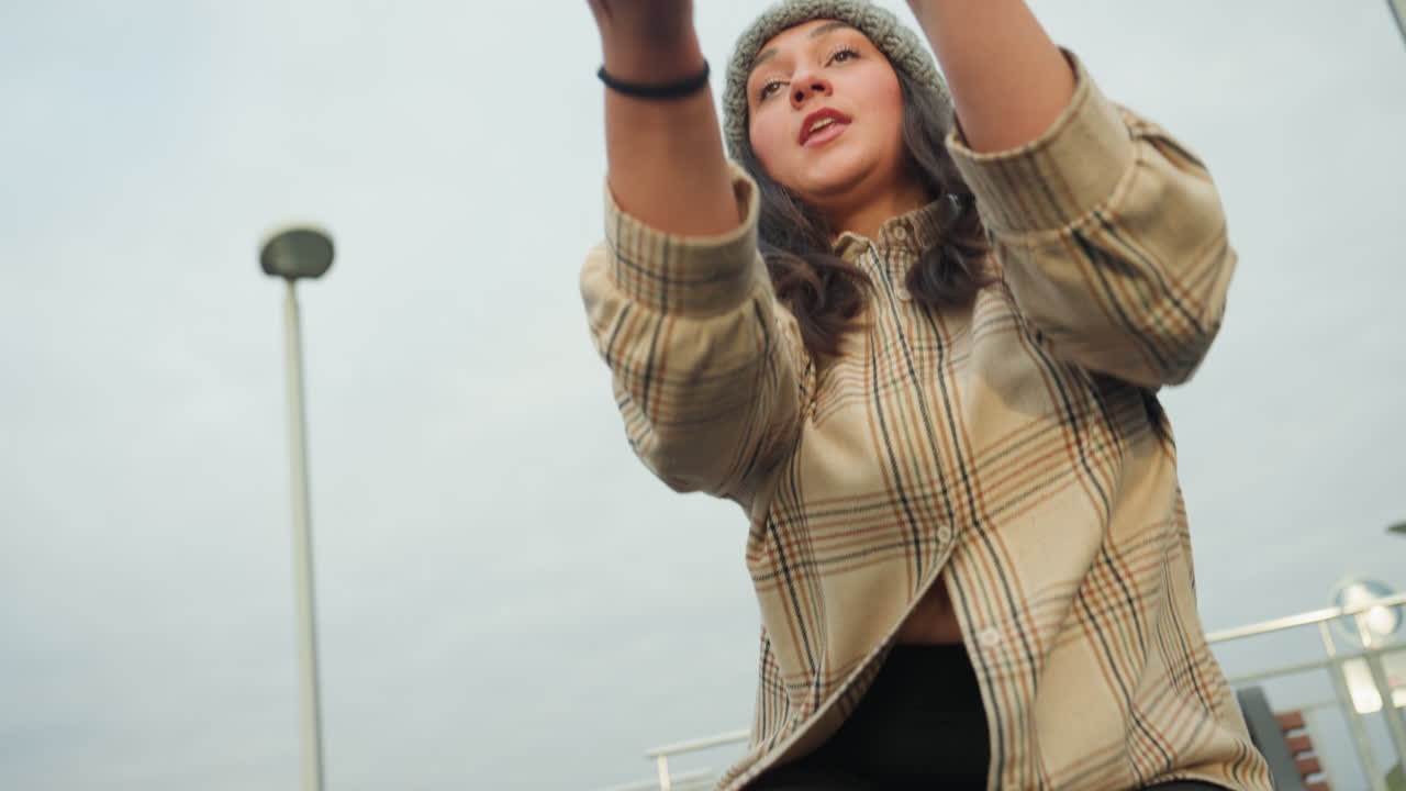 Primo piano di gesti espressivi di danza con le mani e del volto, braccia che si protendono verso lo skyline, dettagli di berretto e camicia a quadri, una narrazione emotiva intima attraverso il movimento, creazione di un artista interpretativo.