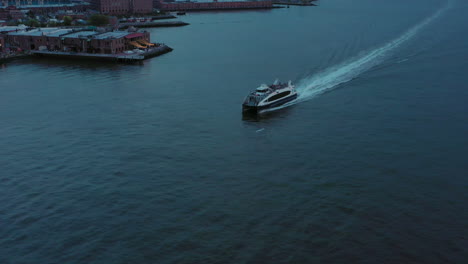 aerial tilt down with ferry boat in new york harbor off of red hook brooklyn at dusk