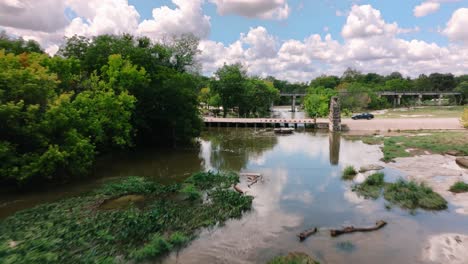 Flying-over-rocky-shore-in-Round-Rock-Texas-Memorial-Park-Chisholm-Trail-aerial-drone-push-in-on-sunny-day-in-4k