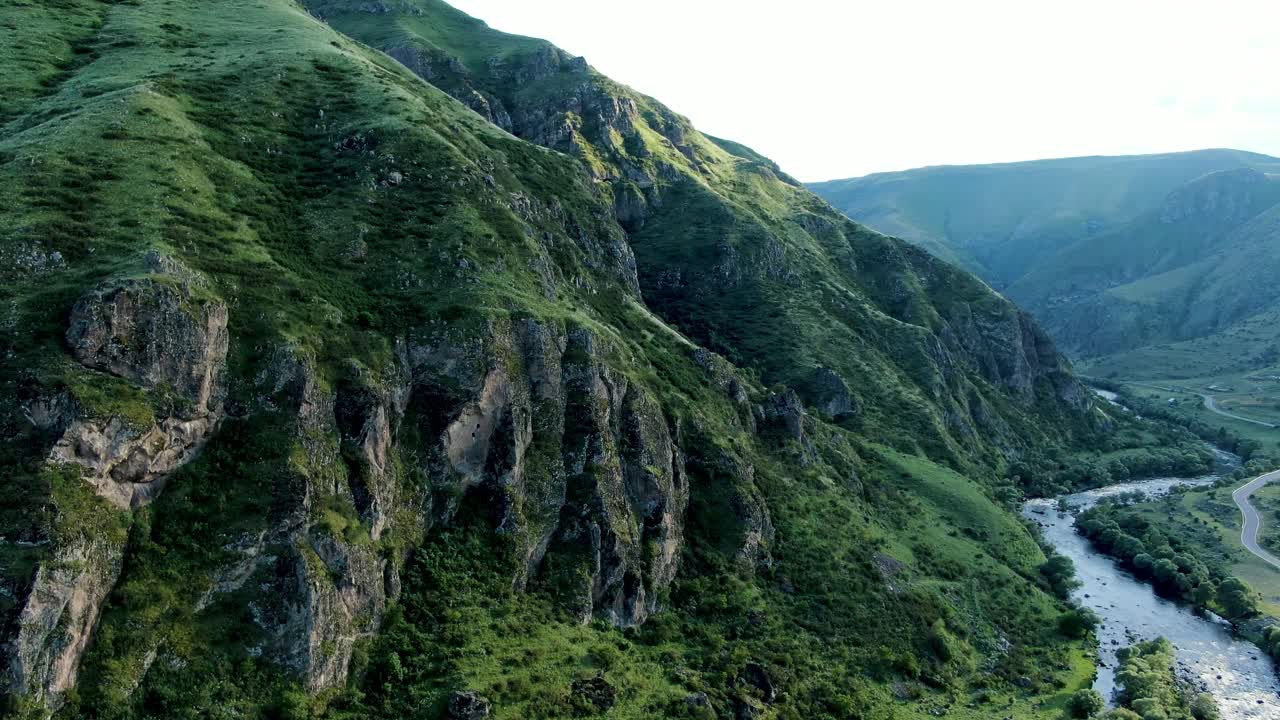 Gunung berbatu besar dekat sungai yang mengalir di Georgia, pemandangan udara drone.