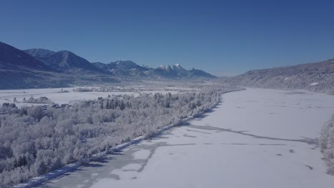 4k aerial video view of alpine snowy valley forest and frozen river in peak of winter overflight - drone collection stock video