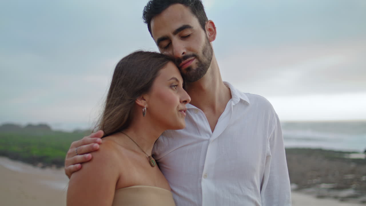 una encantadora familia acurrucada en el océano brumoso de primer plano. una pareja feliz caminando por la playa vertical