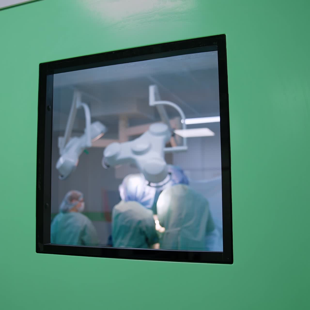 Little window in the door to a surgery room. Doctors' team performing a surgery in the room