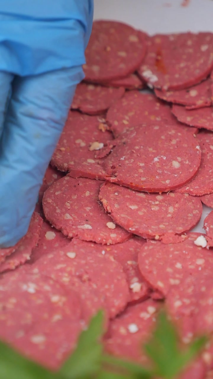 Gloved Hand Arranging Slices of Salami on a Plate