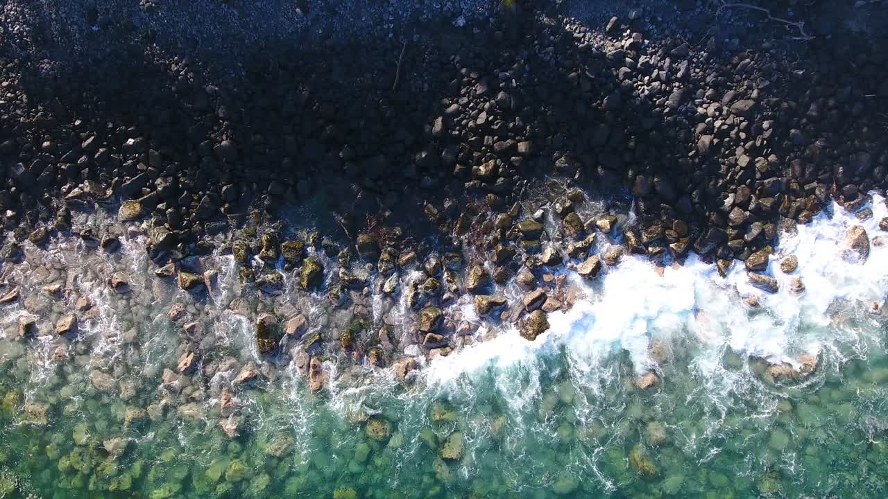 antena strafe aérea de costa rocosa con olas de agua clara rompiendo