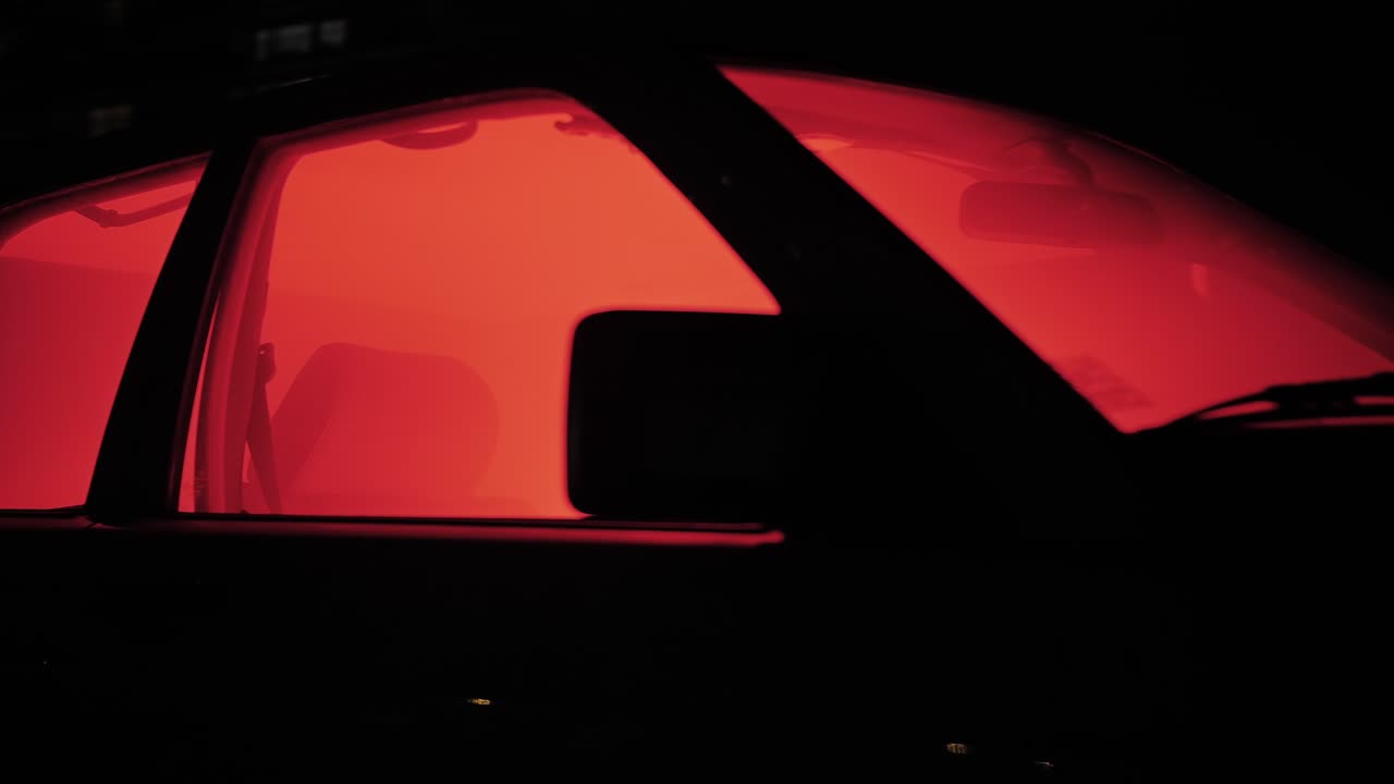 Suspenseful close-up of a car filled with red smoke at night, creating an intense, cinematic crime-thriller atmosphere