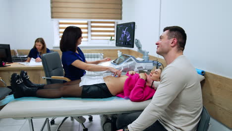 caucasian couple visiting an obstetrician. happy parents see their future baby on the screen of ultrasonic machine.